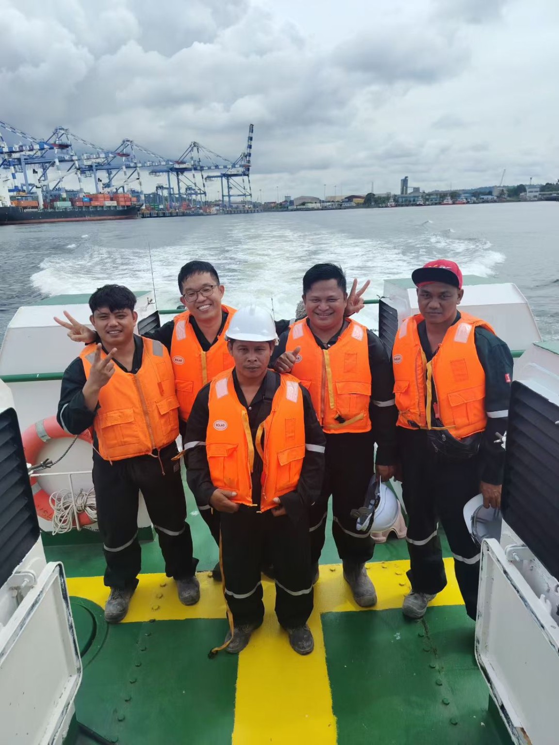 Five Sea Sphere team members wearing orange life jackets aboard a transfer boat